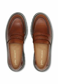 Ruskeat nahkaiset loafferit, joissa teksturoitu, kudottu yläosa, mustat kumipohjat ja kohokuvioitu brändäys sisävuorella.