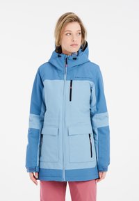Blauwe winterjas met een capuchon, ritszakken en contrasterende kleurblokken. Gemaakt van duurzaam, waterdicht materiaal met een gladde textuur.