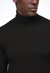 Suéter de cuello alto negro con un diseño ajustado. Textura suave y detalle de cuello acanalado. La costura de contraste no es visible.