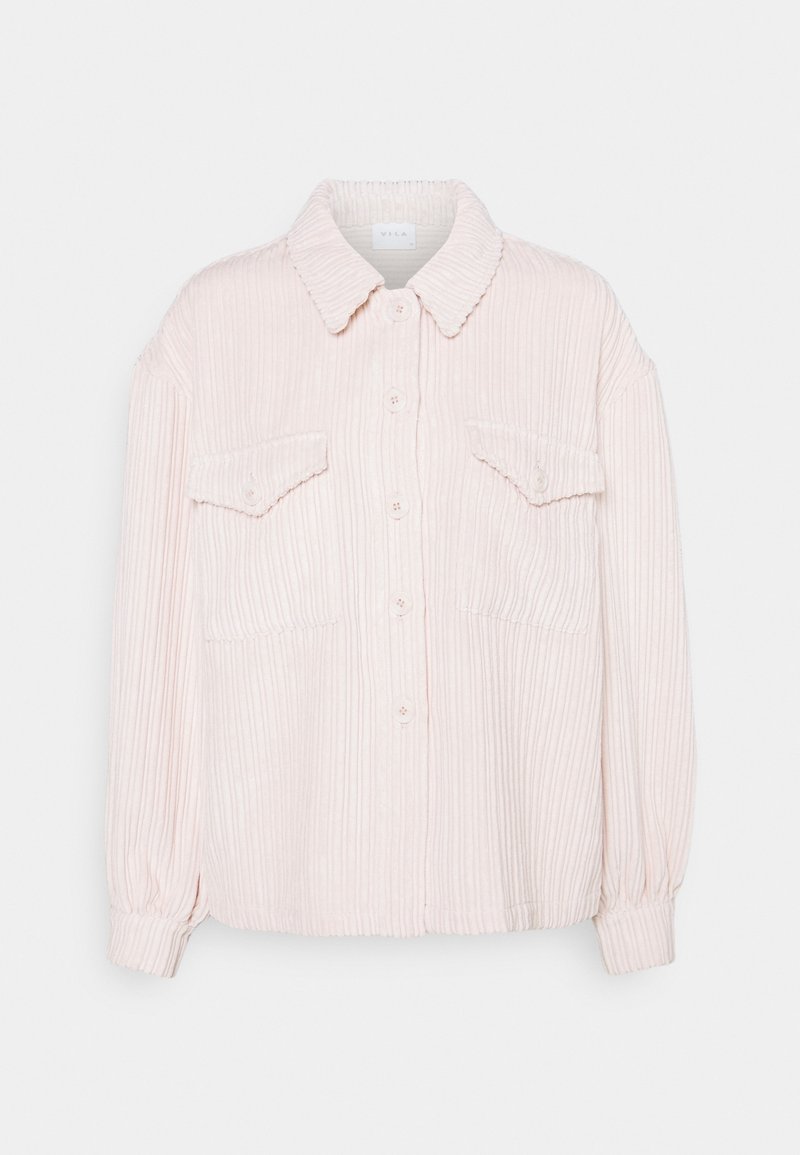 Chemise en velours côtelé rose clair à manches longues avec boutonnage devant, deux poches poitrine à rabat et col classique sur fond blanc.