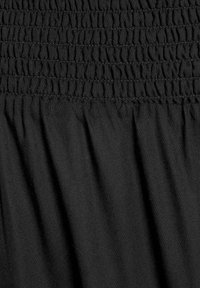 Black fabric featuring a smocked bodice with textured pleating. Smooth surface with subtle sheen, offering flexibility and a comfortable fit.