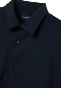 Camicia abbottonata blu navy realizzata in tessuto liscio. Presenta un colletto strutturato, sei bottoni e un'etichetta con il logo "PIOMBO".