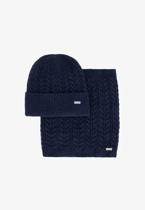 Conjunto de gorro y bufanda de punto azul marino con un patrón de trenzas y detalles acanalados. Ambas piezas incluyen una pequeña etiqueta de la marca.