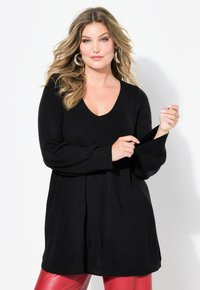 Maglione a costine nero con scollo a V, maniche lunghe e vestibilità comoda. Dettaglio notevole è la fessura al polsino della manica.