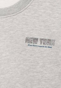 Tessuto grigio chiaro con scollatura a costine e stampa del testo "NEW YORK Dove Nascono le Leggende delle Corse" in un design piccolo e centrato.
