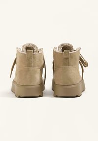 Kahovohned semišové členkové topánky s plyšovou podšívkou, zaoblenou špičkou a hrubou gumovou podošvou s textúrovaným vzorom. Sťahovacie šnúrky a pútko na zadnej strane.