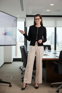Femme avec des lunettes présentant un graphique en hausse sur un grand écran dans une salle de conférence de bureau moderne.