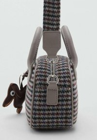 Handväska med hundtandsmönster, grå läderhandtag och dragkedja, med en liten nyckelring i form av en brun hund fäst.