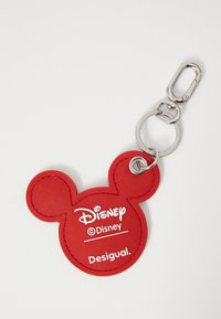 Rode rubberen sleutelhanger in de vorm van het hoofd van Mickey Mouse met witte logo-tekst "Disney" en "Desigual" in een cirkelontwerp. Zilveren metalen hardware.