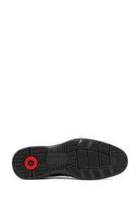 Semelle en caoutchouc noir avec un motif de bande de roulement et un détail circulaire rouge du système d'air près du talon.