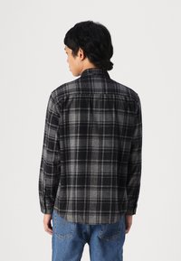 Μαύρο και γκρι καρό πουκάμισο φλοράλ με μακριά μανίκια, κολάρο που κλείνει με κουμπιά και ίσια άκρα. Μαλακή υφή και άνετη εφαρμογή.