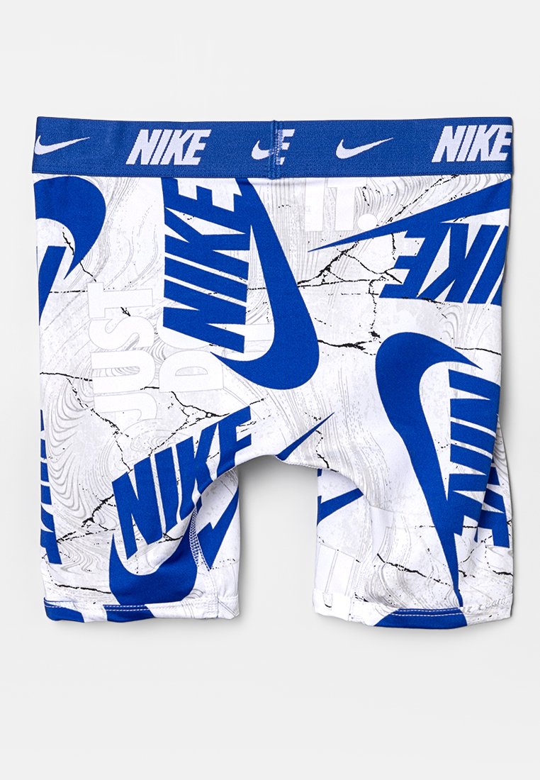 Białe spodenki sportowe z odważnym niebieskim logo Nike i abstrakcyjnym wzorem, z tekstem "Just Do It" wkomponowanym w ten wzór.