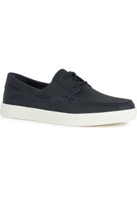 Zapatos náuticos de cuero azul marino con suela de goma blanca, que presentan una superficie texturizada, detalles de costura y cierre con cordones.