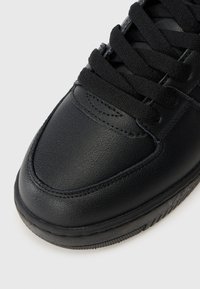 Basket en cuir noir avec un empeigne texturée, lacets plats noirs et bout arrondi. Présente des détails de coutures subtils et une semelle texturée.