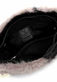Interno nero di una borsa con un morbido bordo in pelliccia grigia. Include un'etichetta nera rettangolare e dettagli con cerniera.