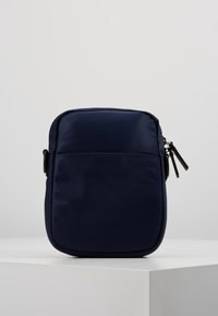 Borsa in nylon blu navy di forma rettangolare, con una tasca frontale e chiusura con cerniera. Texture liscia e design minimal.
