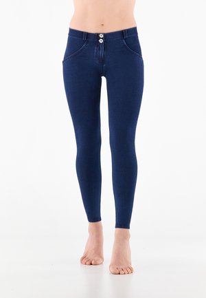 Leggings en denim de couleur bleu foncé avec une taille haute, présentant deux boutons à l'avant, des poches cousues et une texture lisse et extensible.