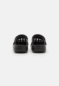 Sabots noirs avec un design perforé, une sangle arrière et une semelle en caoutchouc texturé. Matériau léger et flexible pour un confort optimal.