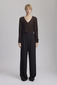 Brown long-sleeve wrap top paired with high-waisted black pinstripe wide-leg trousers, featuring cuffed sleeves and a tailored fit.