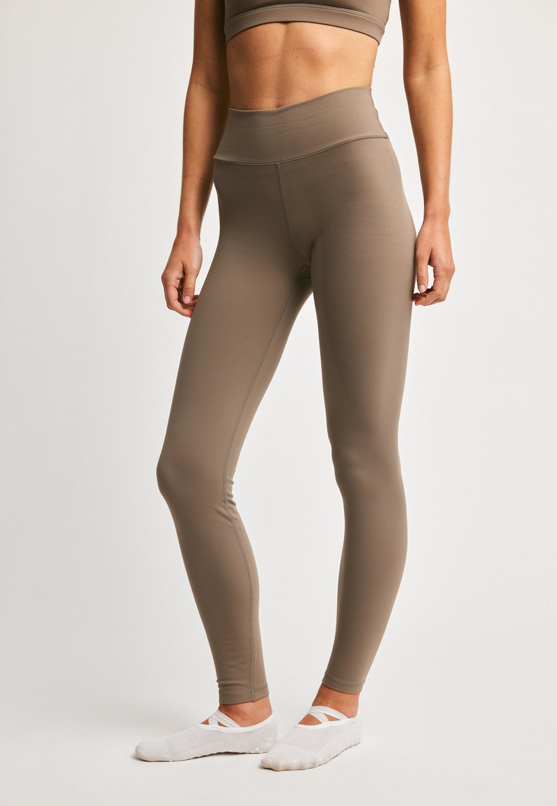 Brune høytliv leggings laget av elastisk stoff med en jevn tekstur, med flatlock-sømmer for komfort og en strømlinjeformet passform.