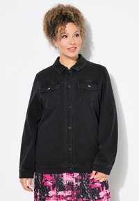 Svart denimjacka med krage, två bröstfickor och knappstängning. Tyget har en lätt struktur som kompletterar en färgglad plisserad kjol.