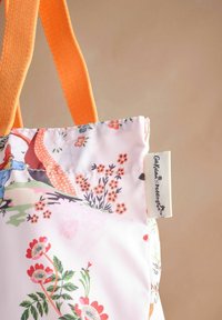 Borsa a tracolla floreale in tessuto rosa con manici intrecciati arancioni. Presenta intricati motivi di fiori e foglie, e un'etichetta cucita sul lato.