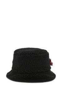 Chapeau seau noir en polaire texturée. Présente une forme ronde et douce avec un accent rouge unique sur le côté. Pas de matériel visible.