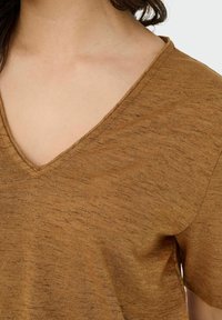 Bruine gestructureerde top met een V-hals ontwerp en korte mouwen. De stof heeft subtiele metallic draadjes voor extra detail.