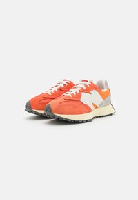 Orange- und weiße Sneaker mit einem Obermaterial aus Wildleder und Mesh, Gummisohle, Schnürverschluss und einem grauen Wildlederakzent an der Ferse.