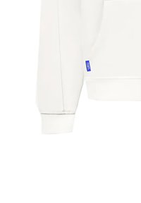 White sweatshirt with a kangaroo pocket, ribbed cuffs, and hem. Features a blue label on the left side. Smooth texture and simple design.