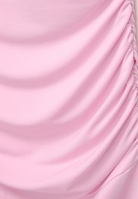 Tissu rose doux avec un détail de fronces rassemblées le long du côté droit créant de doux plis et une texture.