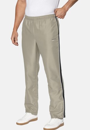 Hellgraue Sporthose mit glatter Textur, ausgestattet mit einem schwarz-weißen Seitenstreifen und einem elastischen Bund. Kombiniert mit weißen Sneakers.