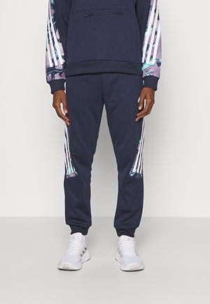 Pantaloni da jogging blu navy con dettagli a strisce bianche e un motivo grafico colorato sul lato. Realizzati in tessuto morbido, con polsini e vita elastica.