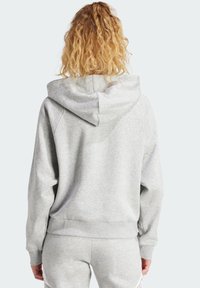 Sweatshirt gris avec capuche, offrant une coupe décontractée, des poignets et un ourlet côtelés. Texture douce et éléments de design simples.