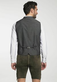 Grau gefütterte Stoffweste mit glatter Textur, ausgestattet mit einem Rückenschnürung und einem gemusterten Kragen, getragen über einem weißen Hemd und braunen Shorts.