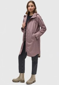 Water-resistant pinkish-purple coat with hood, zip closure, front pockets, and a relaxed fit, paired with dark jeans and beige ankle boots.