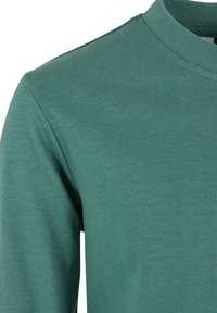 Kurzarm-T-Shirt mit Rundhalsausschnitt in Türkis, aus weicher Baumwolle gefertigt. Es zeichnet sich durch eine glatte Textur und ein einfaches Design ohne sichtbare Muster oder Akzente aus.