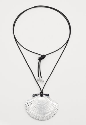 Pendente em forma de concha prateada, preso a um cordão ajustável preto com extremidades metálicas. Possui textura estriada e um acabamento suave.