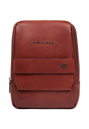 Bolso bandolera compacto de cuero marrón con cierre de cremallera, bolsillo frontal con solapa y logotipos metálicos de la marca en la parte delantera.