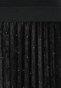 Zwarte geplooide rok met een gestructureerde, fluweelachtige afwerking. Heeft een effen zwarte tailleband en verspreide rhinestones voor extra detail.