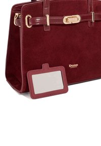 Burgundy suede handbag with glossy patent leather accents, gold hardware, and a detachable ID tag. Smooth texture and structured design.