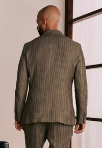 Brown striped linen suit jacket with a tailored fit, notch lapels, and buttoned cuffs, viewed from the back, showing clean lines and subtle texture.
