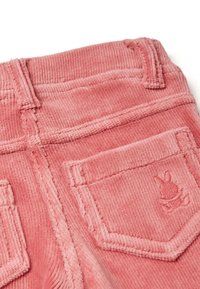 Růžové sametové šortky s texturovaným povrchem, zadními kapsami a vyšitým králičím logem na pravé kapse.
