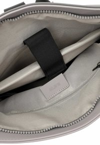 Graue Tasche innen mit glattem Stofffutter, einem schwarzen Tragegriff, einer Reißverschlusstasche und einem Etikett mit der Aufschrift "RU 09." Merkmale ein elegantes, minimalistisches Design.