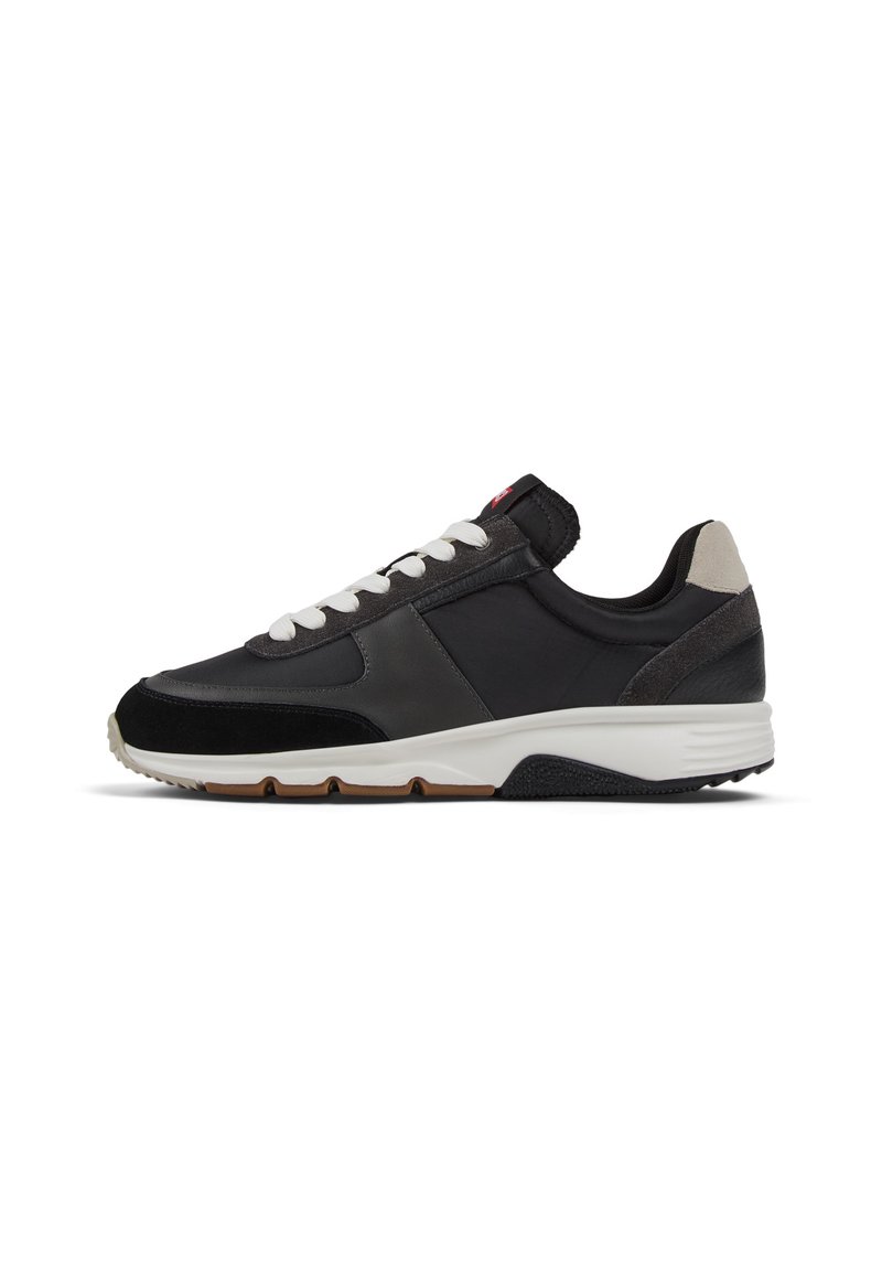 Niskoprofilowy czarny sneaker z białymi sznurowadłami, szarym akcentem na pięcie i białą podeszwą z brązowymi i czarnymi sekcjami bieżnika.