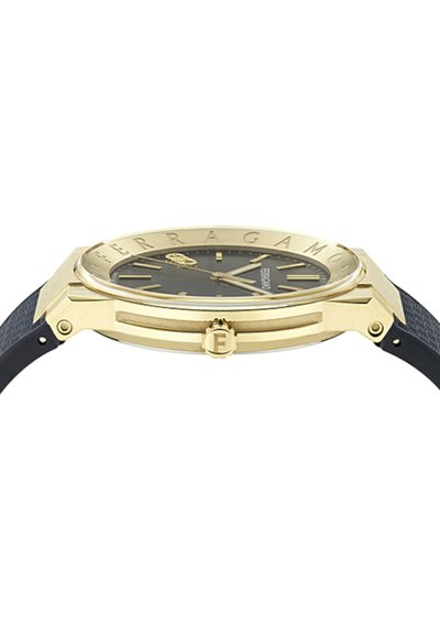 Zelta tonī Ferragamo rokas pulkstenis ar melnu ciparnīcu, zelta stundu marķieriem un melnu teksturētu siksniņu, redzams no sānu skata.