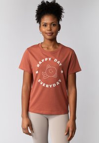 Korte mouwen, roestkleurig katoenen t-shirt met een ronde hals. Voorzien van witte tekst: "HAPPY DAY EVERYDAY" en een glimlachend karakter grafiek.