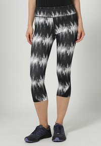 Czarno-białe leginsy capri w wzory o smukłym kroju, wykonane z elastycznego materiału, z szerokim pasem i gładkimi szwami.