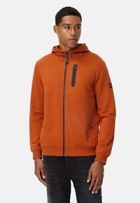 Orange zip-up hættejakke med snoretræk i hætten, sort lynlås brystlomme, sidelommer og ribbede manchetter, lavet af blødt stof.