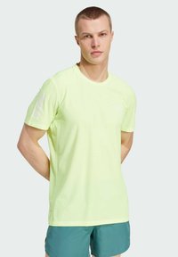 Camiseta deportiva de color amarillo neón, con manga corta, cuello redondo y tres rayas blancas en el hombro izquierdo. Tela ligera y transpirable.